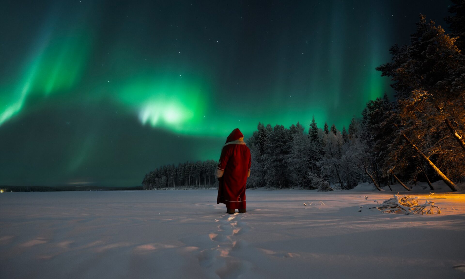 Santa Claus on a frozen lake witnessing Northern Lights. Rovaniemi, Lapland, Finland. | Santa Claus Secret Forest