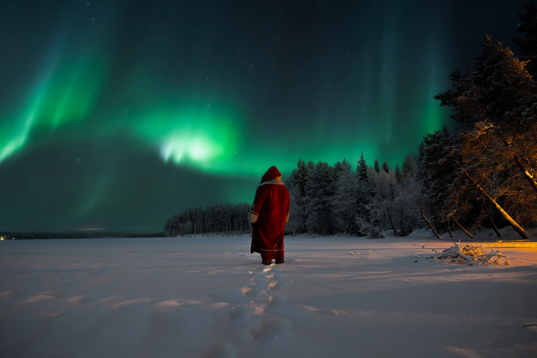 Santa Claus on a frozen lake witnessing Northern Lights. Rovaniemi, Lapland, Finland. | Santa Claus Secret Forest